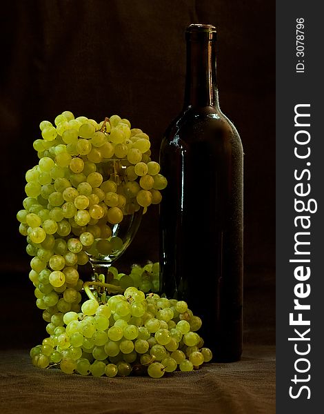 White grapes and bottle of wine on black background
