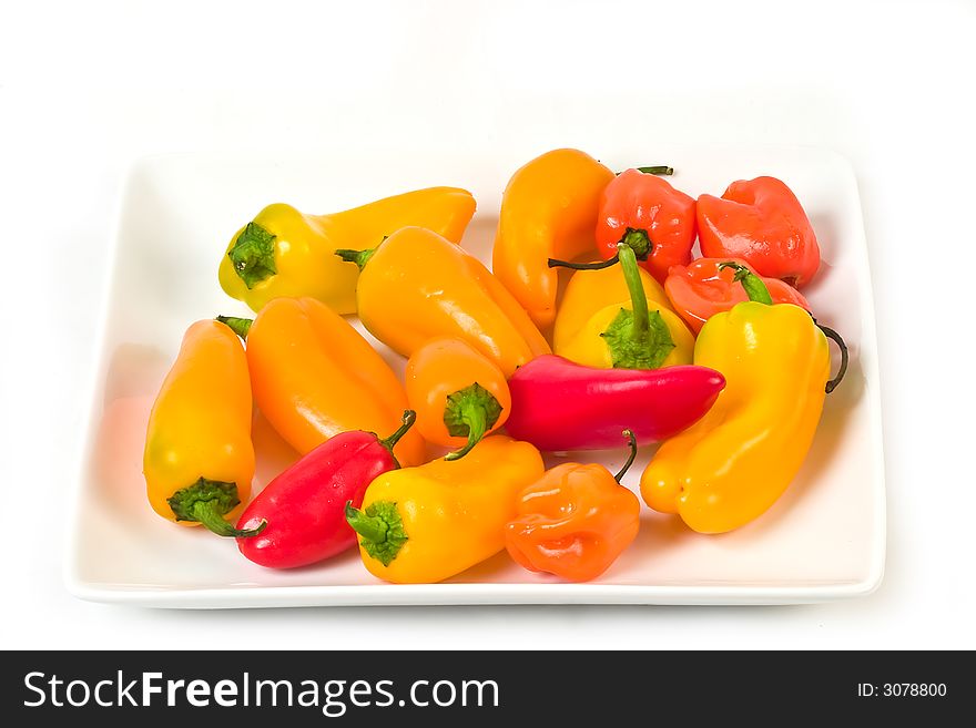 Orange and red sweet peppers on white plate. Orange and red sweet peppers on white plate
