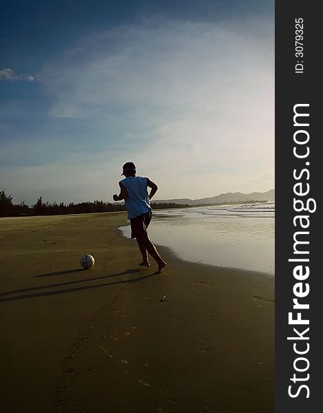 A guy kicking a soccer ball around in the beach. A guy kicking a soccer ball around in the beach