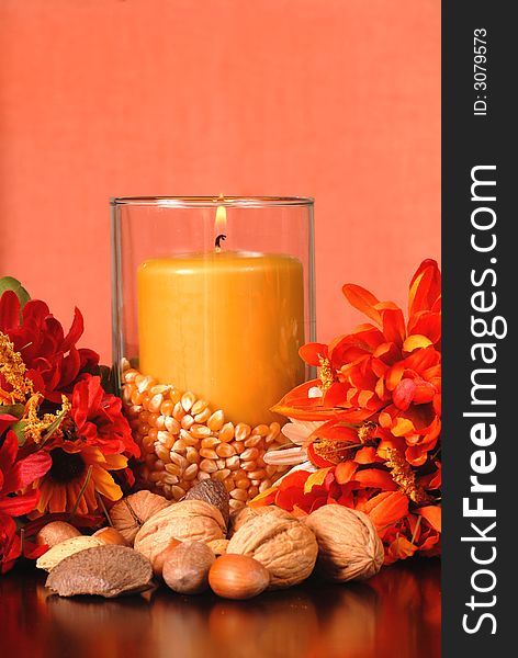 Candle in an autumn setting surrounded with nuts and flowers. Candle in an autumn setting surrounded with nuts and flowers