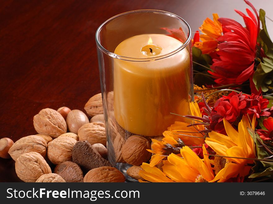 Candle in an autumn setting with nuts and flowers. Candle in an autumn setting with nuts and flowers