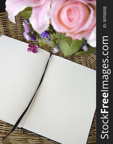 Blank page of notebook put on basket with flowers. Blank page of notebook put on basket with flowers