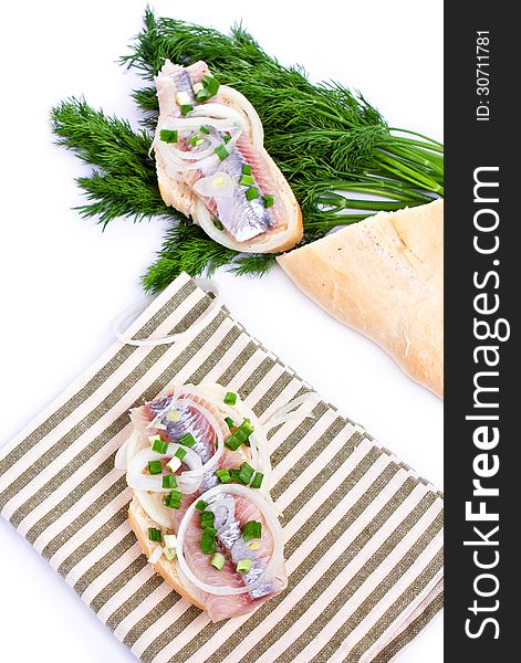 Sandwiches of white bread with herring, onions and herbs on white background