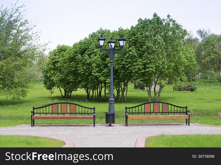 Classic style city lamp and wooden benches in green springtime park. Classic style city lamp and wooden benches in green springtime park