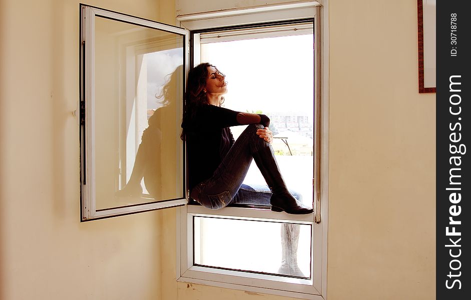 Portrait of beautiful woman sitting on the window