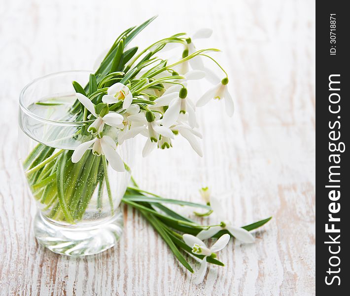 Bouquet of snowdrop flowers in  vase, on a old wooden background