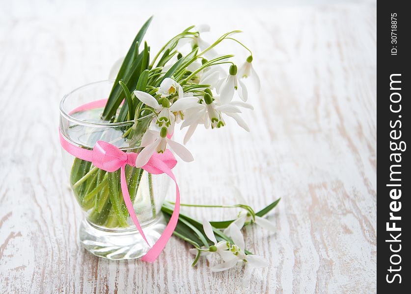 Bouquet of snowdrop flowers in  vase, on a old wooden background