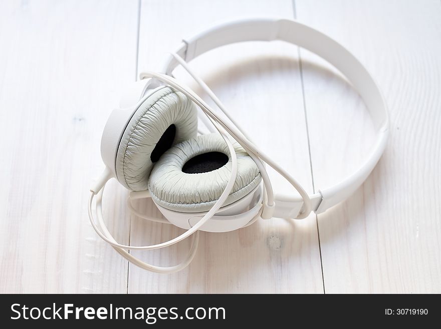 White headphones lying on wooden background. White headphones lying on wooden background