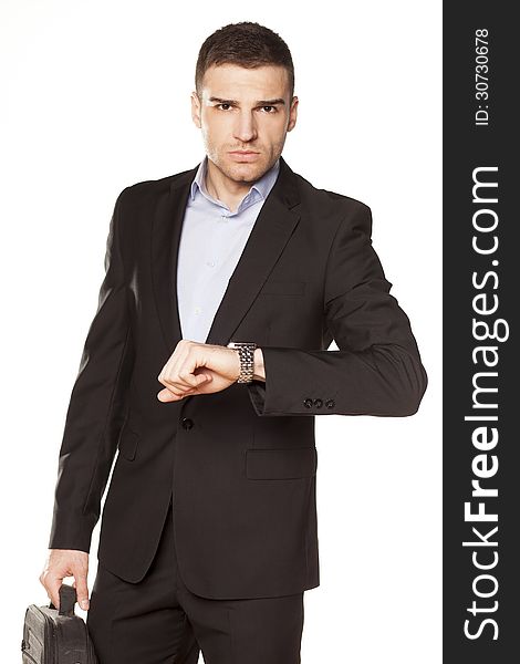 Attractive young businessman looking at his watch with a laptop bag in the other hand