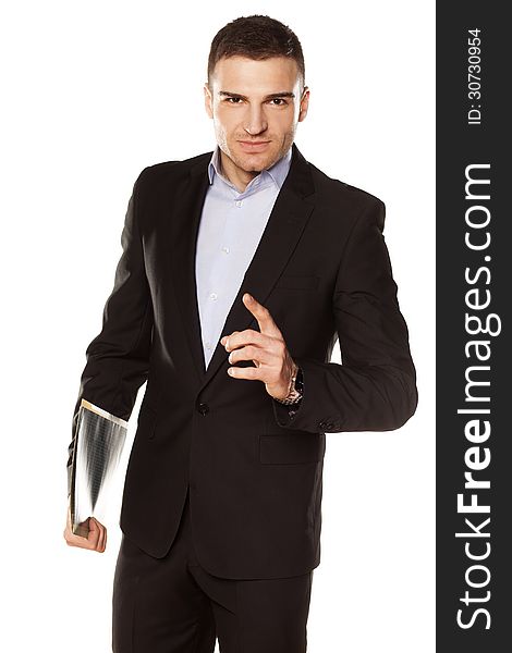 Smiling young businessman with folder in hand pointing a finger upwards