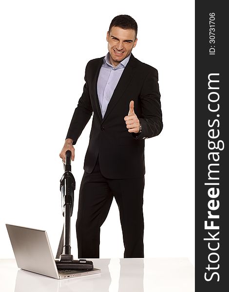Smiling and attractive young businessman vacuum cleans his laptop and showing thumbs up. Smiling and attractive young businessman vacuum cleans his laptop and showing thumbs up
