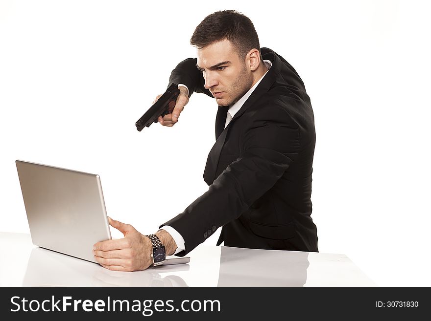 Mad and angry young businessman destroying his laptop using guns. Mad and angry young businessman destroying his laptop using guns