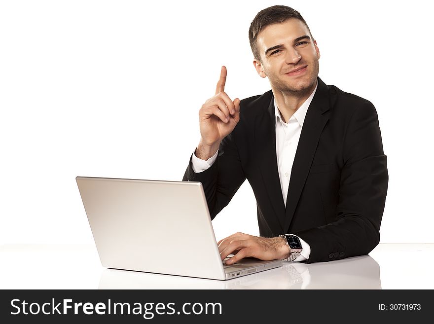 Smiling young and attractive businessman shows his finger up behind his laptop. Smiling young and attractive businessman shows his finger up behind his laptop