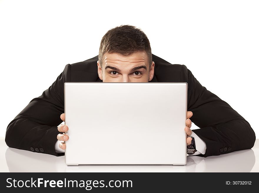 Young and funny businessman hiding behind his laptop. Young and funny businessman hiding behind his laptop