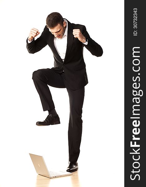 Young and attractive furious businessman in black suit, destroying his laptop using his foot. Young and attractive furious businessman in black suit, destroying his laptop using his foot
