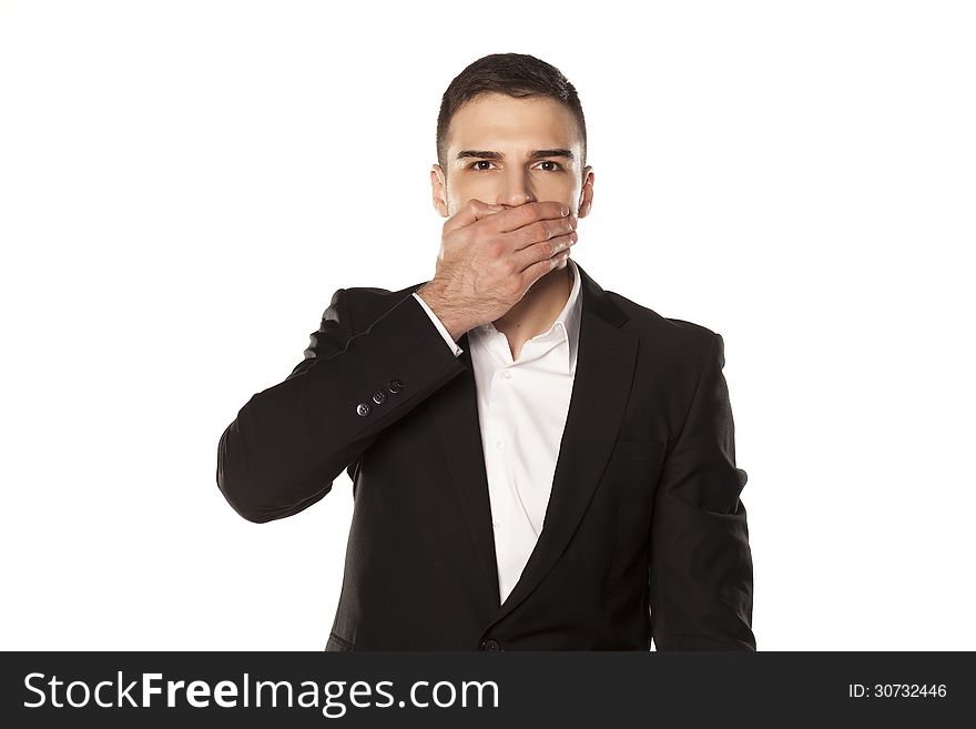 Young and attractive serious businessman in black suit, covering his mouth with his hand. Young and attractive serious businessman in black suit, covering his mouth with his hand