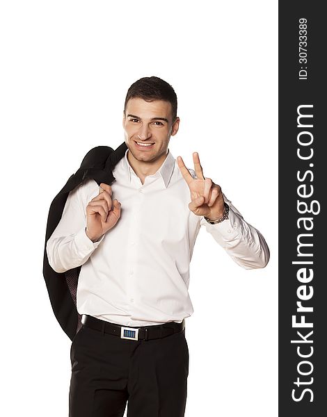 Young and attractive businessman smiling in a white shirt with a jacket over his shoulder, showing two fingers up