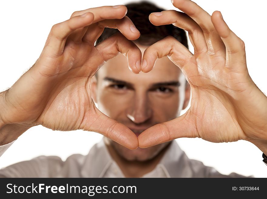 Smiling attractive young man makes the heart using fingers. Smiling attractive young man makes the heart using fingers