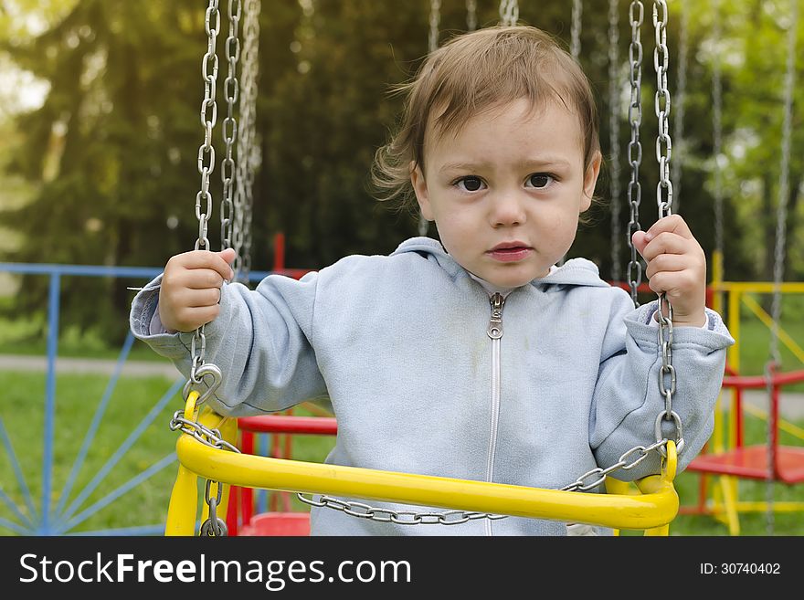 A portrait of a toddler or child, boy or girl, on a chain swing. A portrait of a toddler or child, boy or girl, on a chain swing.