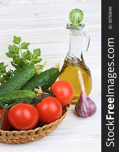 Vegetables and a bottle of olive oil on a light wooden background