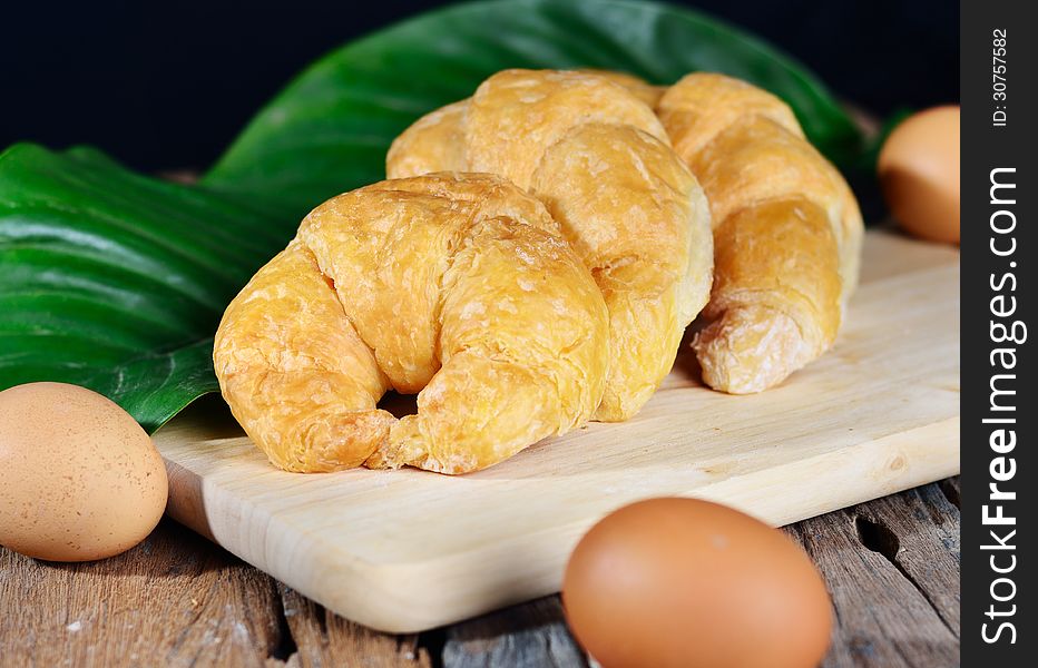 Fresh french croissant with eggs on wood background