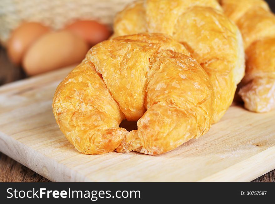 Fresh french croissant with eggs on wood background