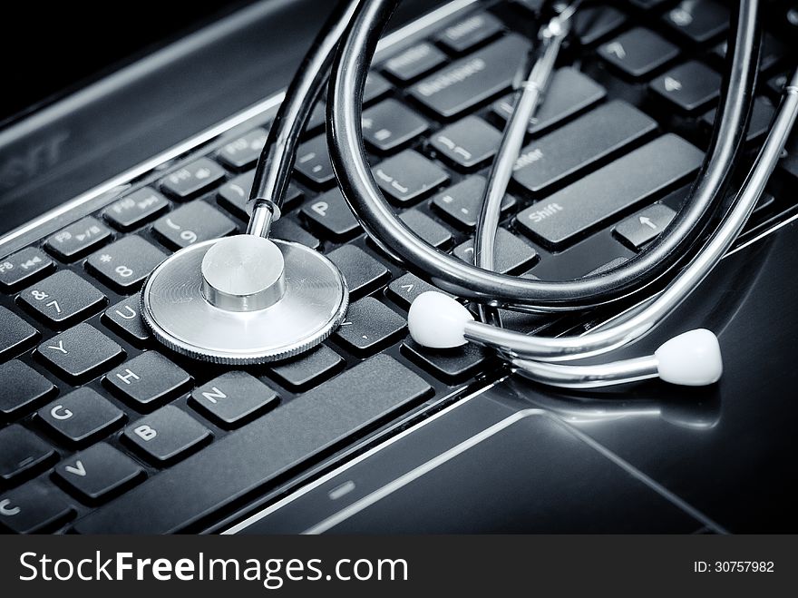 Silver stethoscope lying down on an laptop