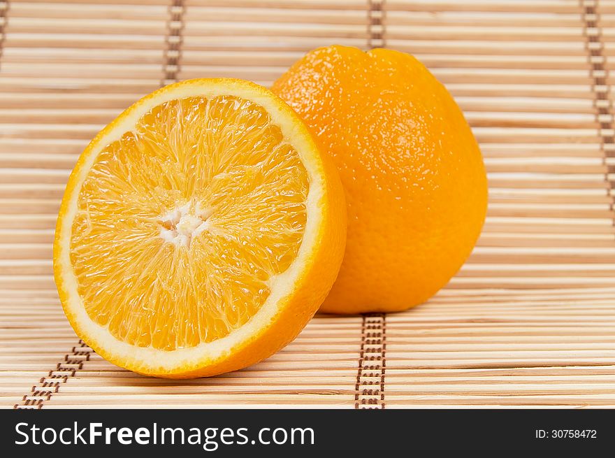 Whole orange fruit and his segments on bamboo background