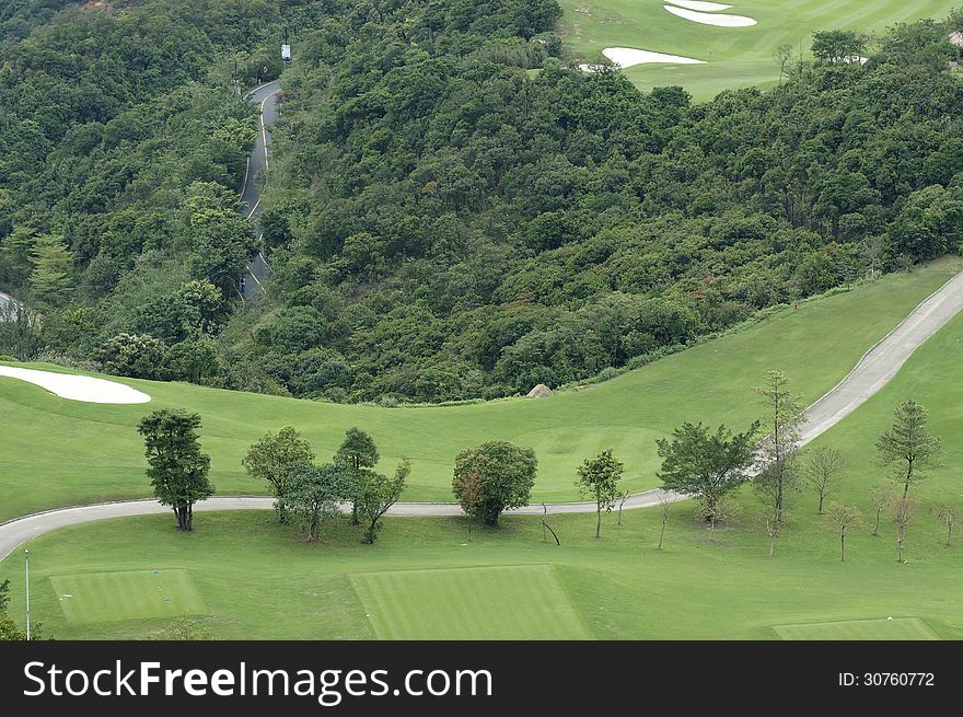 Golf course beside green wood.