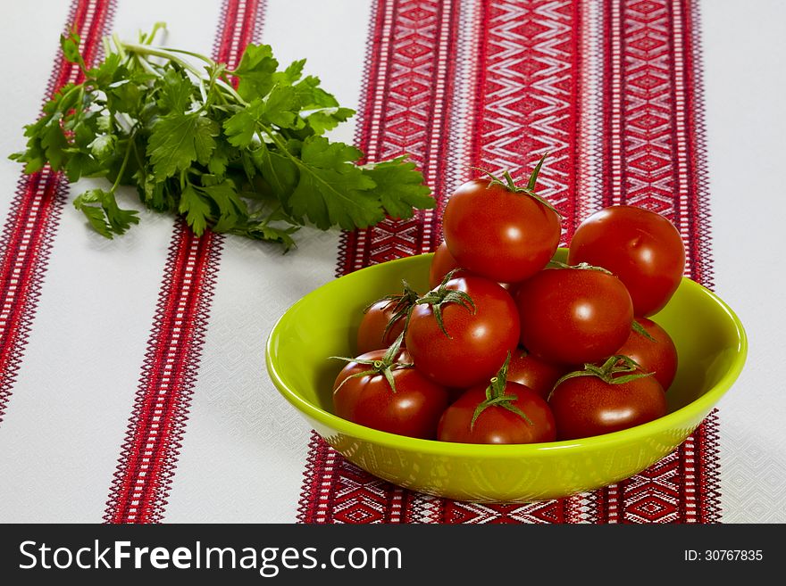 On the table ripe tomatoes in green bowl and parsley. On the table ripe tomatoes in green bowl and parsley