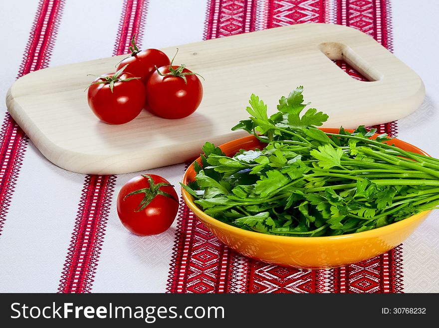 Tomatoes on a cutting board and parsley in a bowl. Tomatoes on a cutting board and parsley in a bowl