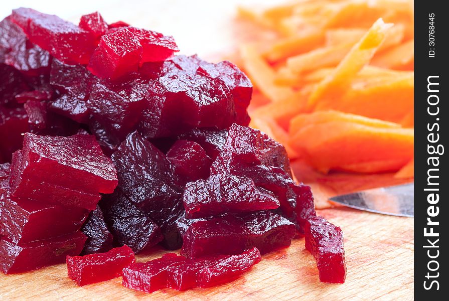 Cutting of boiled beets against knife and carrots