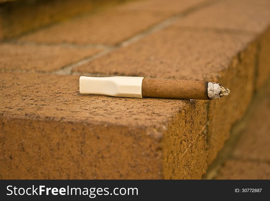 Closeup of a cigar left on a brick step.