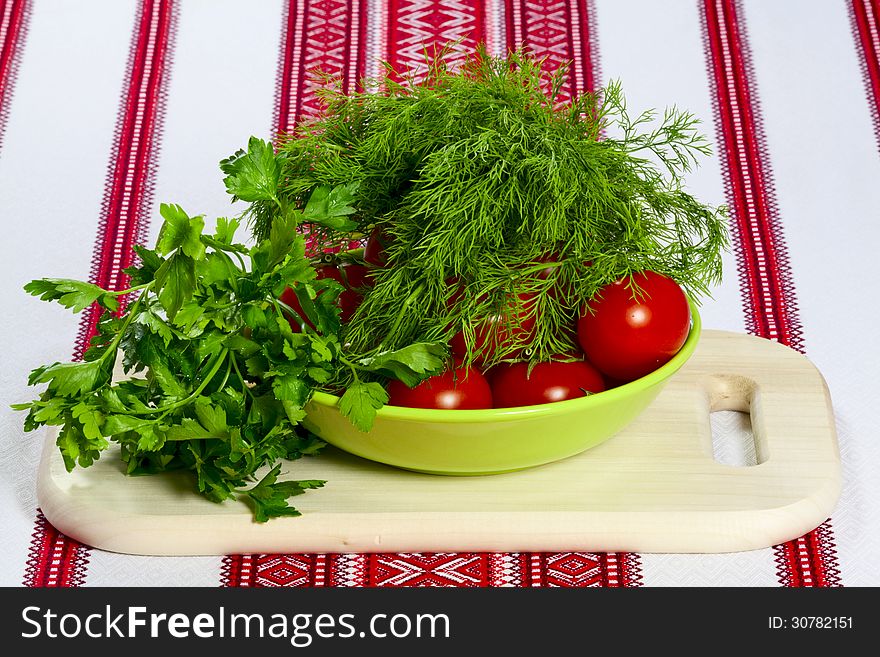 Ripe tomatoes in green bowl and fresh herbs on cutting board. Ripe tomatoes in green bowl and fresh herbs on cutting board