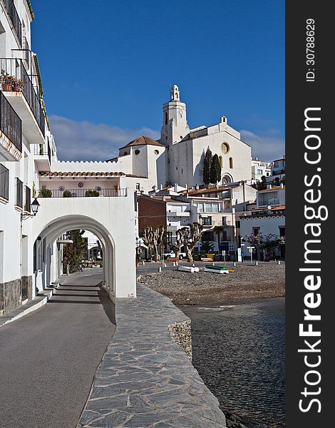 Clear blue sky day in Cadaques, Spain with Church of Santa Maria in the background and famous arches in foreground. Clear blue sky day in Cadaques, Spain with Church of Santa Maria in the background and famous arches in foreground