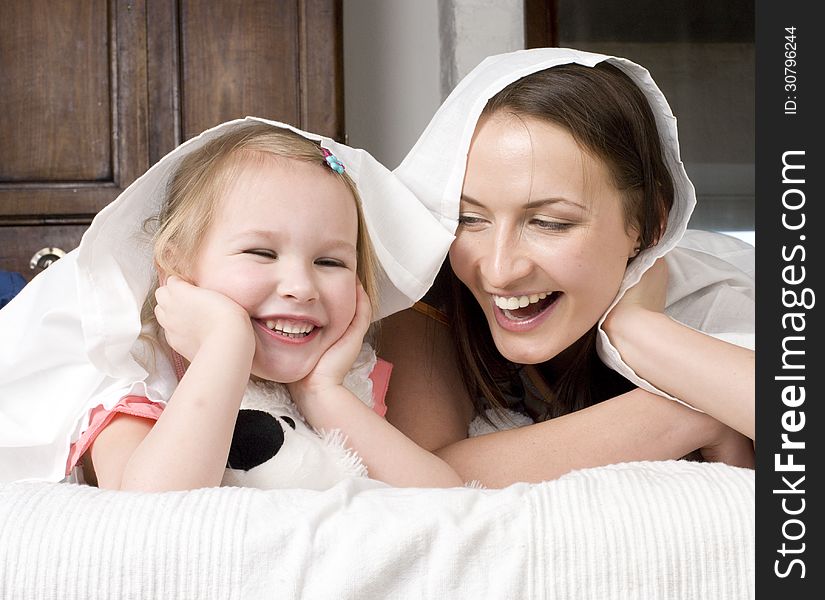 Portrait Of Happy Mother And Daughter In Bed Hugging And Smiling