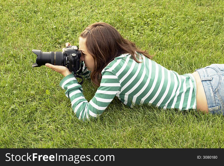 Girl lying with photo camera on grass