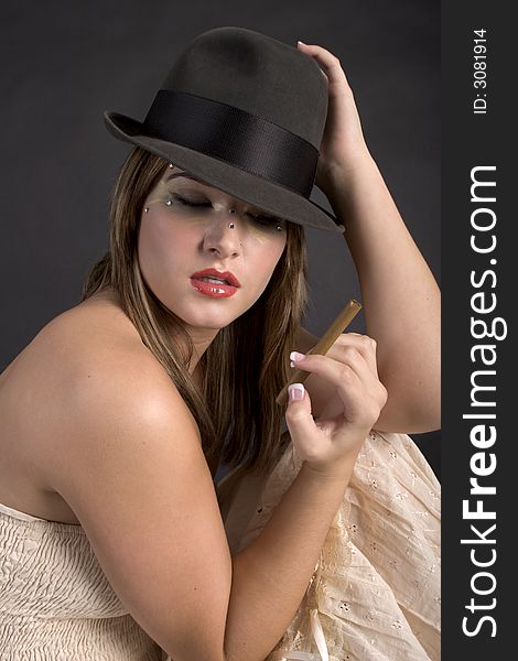Pretty young woman wearing a man's hat and holding an unlit cigar. Pretty young woman wearing a man's hat and holding an unlit cigar