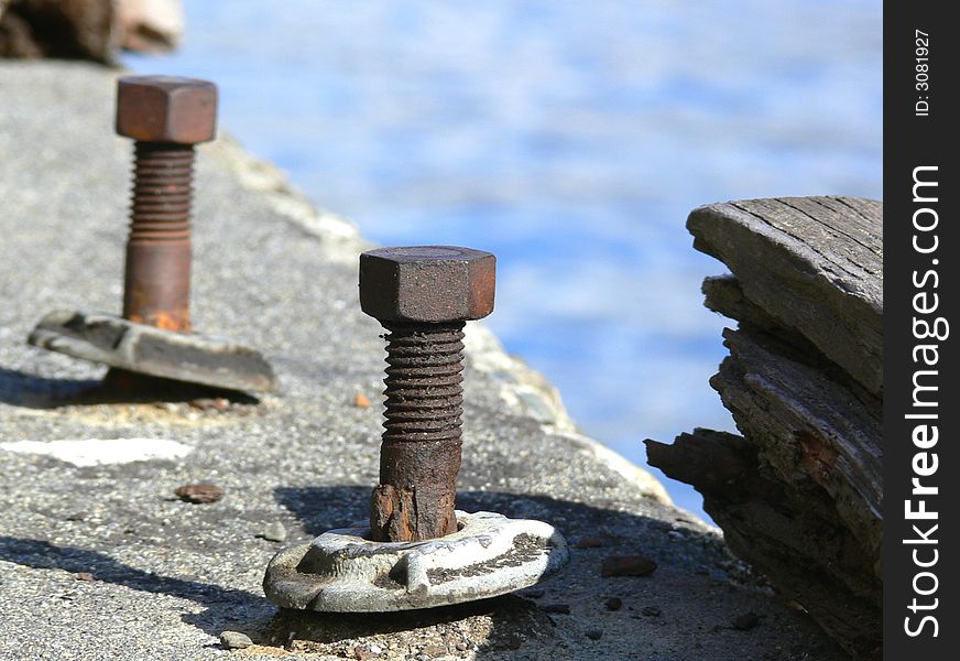 A shot of two old bolts mounted to concrete. A shot of two old bolts mounted to concrete