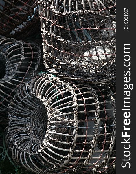 A bunch of fishing traps, stacked on top of one another. they are made of metal and rope woven together. The colors are grey, whites, turquoise, and rust.