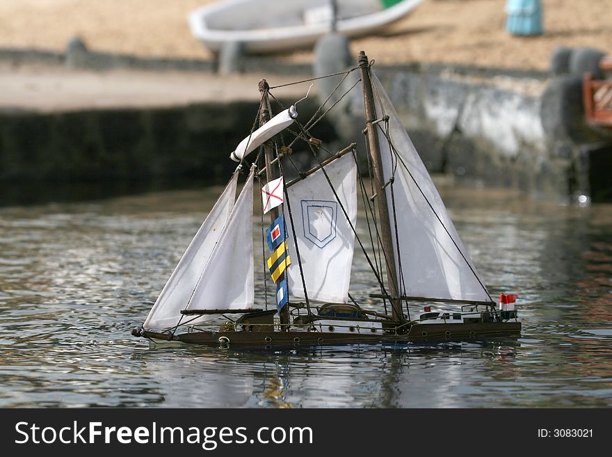 Miniature wooden sail boat mockup sinking in harbor. Miniature wooden sail boat mockup sinking in harbor