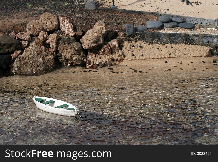 Miniature wooden boat at anchor on a sand beach