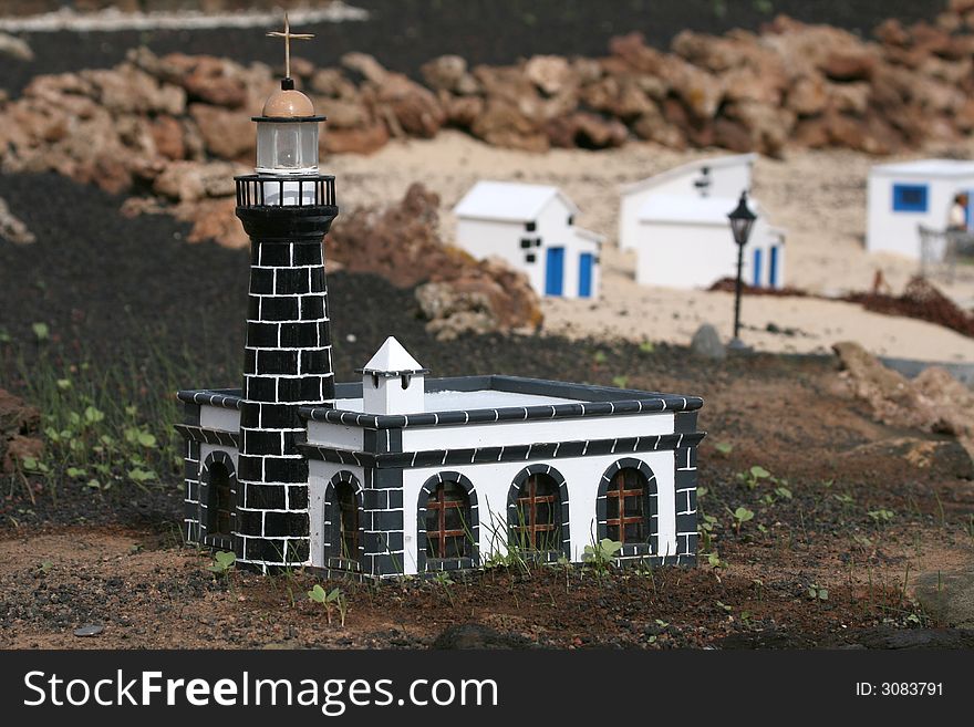 Miniature black and white lighthouse on a beach