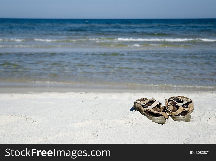 Pair of sandals on the beach, ocean in background