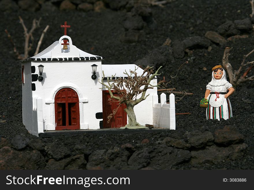 Miniature spanish woman in front of white church. Miniature spanish woman in front of white church