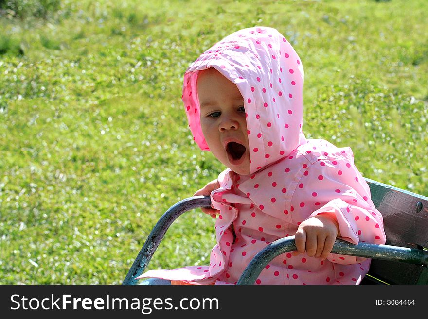 Baby sitting on the chair (carousel) in the garden and yawning. Baby sitting on the chair (carousel) in the garden and yawning