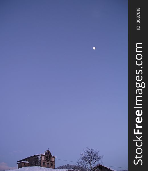 A small rural church at dusk and the moon