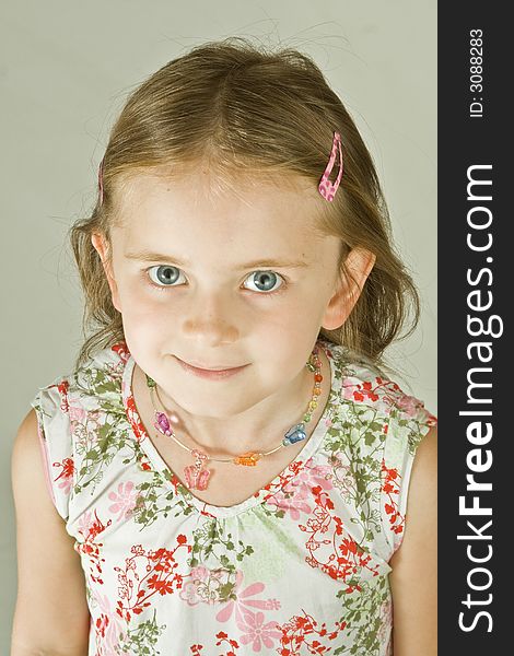 Smiling young girl in a print dress.  Plain background, head and shoulders portrait.