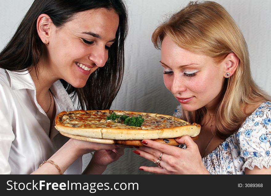 Two girls consider an appetizing pizza. Two girls consider an appetizing pizza