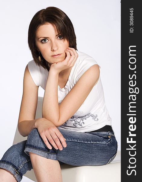 Beautiful brunette girl wearing white T-shirt and jeans on white background. Beautiful brunette girl wearing white T-shirt and jeans on white background